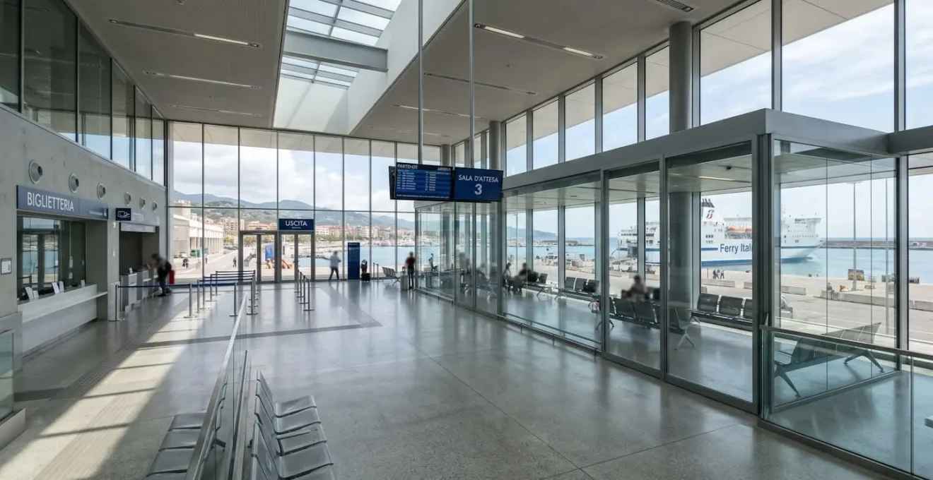 Interno luminoso di un terminal portuale italiano moderno con ampie vetrate e insegna Corsica Ferries visibile sullo sfondo